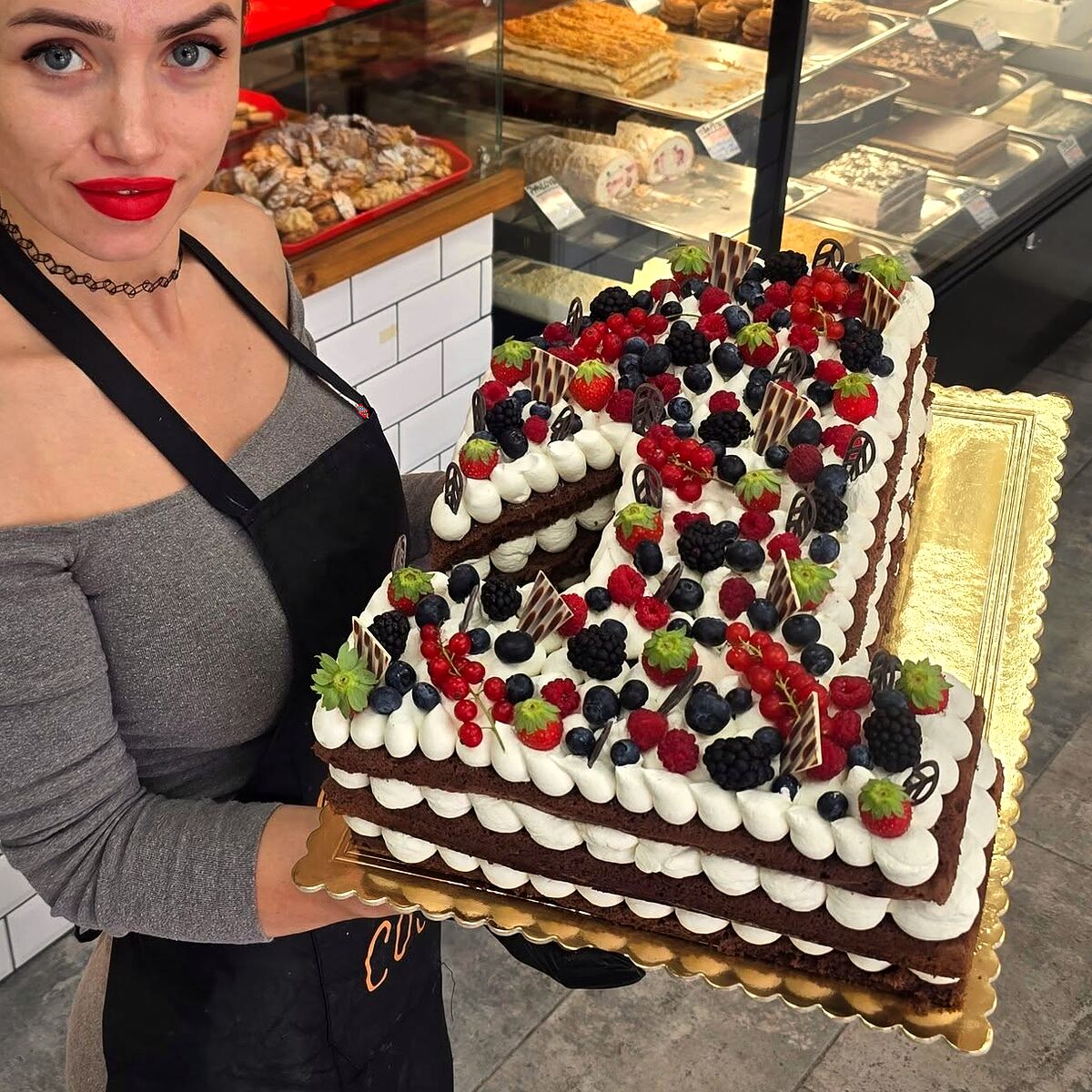 Tort personalizat cu fructe de pădure, ținut în mâini la vitrină